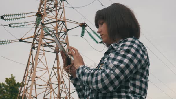 Les femmes utilisent Tablet PC sur fond prend en charge les lignes électriques à haute tension — Video