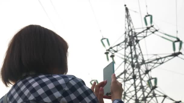 Menina usar Smartphone no fundo suporta linhas de energia de alta tensão — Vídeo de Stock