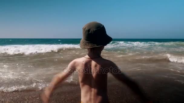 Gelukkig kind spatten in de branding op een zomer-strand — Stockvideo