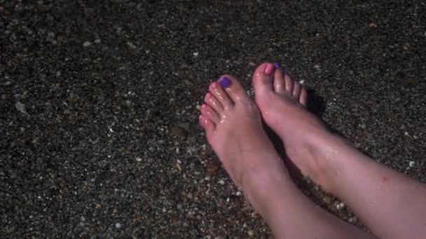 Ocean waves washing over woman feet — Stock Video
