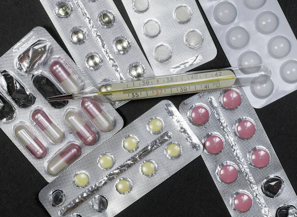 Farklı renk ve bir termometre tıp hapları blister paketleri yığını