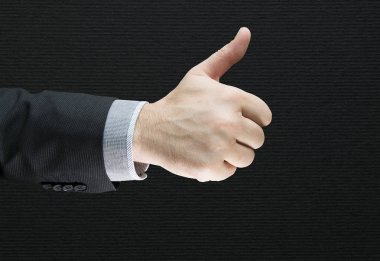 Ok işaret gösteren işadamı onun başparmak ile siyah arka plan ile izole. Başarı iş anlaşması. İş takım elbiseli adamı bir işareti iki el parmakları Tamam gösterir. 