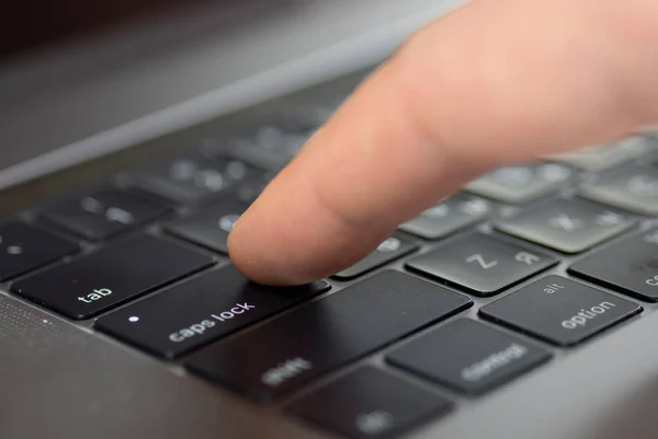 Close-up male finger type key caps lock