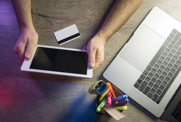 Mãos masculinas segurando tablet pc com tela preta, cartão de crédito e usando laptop. Conceito de compras online. Vista superior — Fotografia de Stock