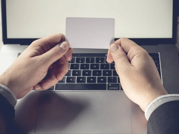 Empresário segurando um cartão branco em branco em um fundo de laptop — Fotografia de Stock