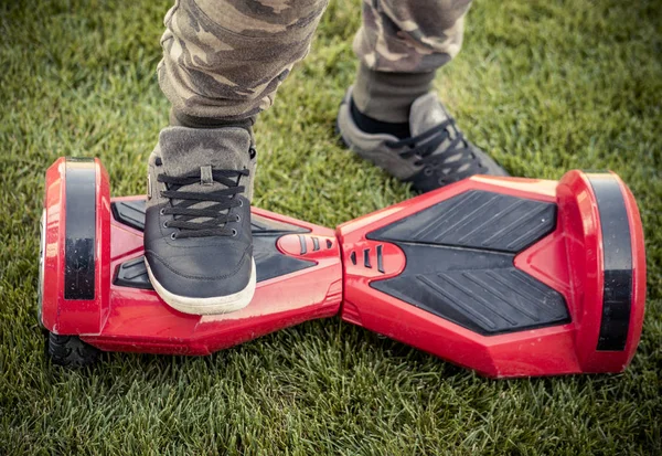 Caddede kırmızı gyroscooter platform üzerinde duran mavi spor ayakkabı bacak erkeklerde. Elektrikli scooter, hoverboard, gyroboard veya gyroscooter kullanmaya başlayın.