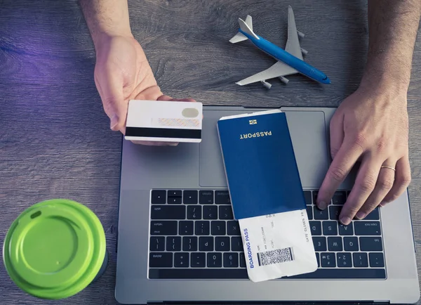 Kredi kartları, dizüstü bilgisayarda arka plan pasaport ve biniş kartı - üstten görünüm yazarak adamın ellerini tutun