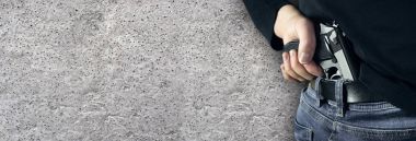 Elinde bir silah siyah kazak ve mavi jeans ile kopya alanı ile adam katil. Onun tutan adam onun açık siyah bir tabanca ver. Kopya alanı ile beton arka plan izole.