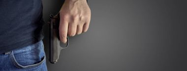 Elinde bir silah siyah kazak ve mavi jeans ile kopya alanı ile adam katil. Onun tutan adam onun açık siyah bir tabanca ver. Kopya alanı ile siyah arka plan izole.