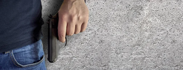 Elinde bir silah siyah kazak ve mavi jeans ile kopya alanı ile adam katil. Onun tutan adam onun açık siyah bir tabanca ver. Kopya alanı ile beton arka plan izole.