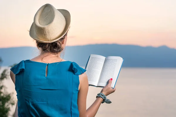Woman reading a book with a sunset view — Stock Photo, Image