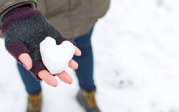 Руки женщины держат снежок в форме сердца — стоковое фото