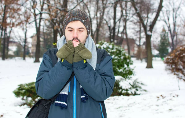 Homem aquecendo as mãos no parque coberto de neve — Fotografia de Stock