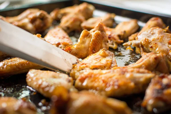 Barbekü tavuk kanadı tutarak maşa pişirme — Stok fotoğraf