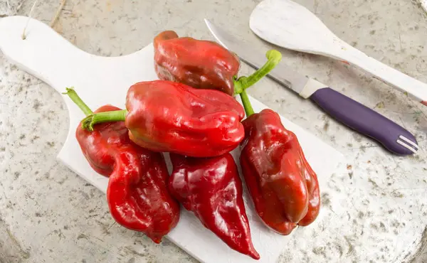 Red bell peppers on a cutting board — Stock Photo, Image