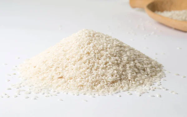 Pile of rice and wooden spoon on white — Stock Photo, Image