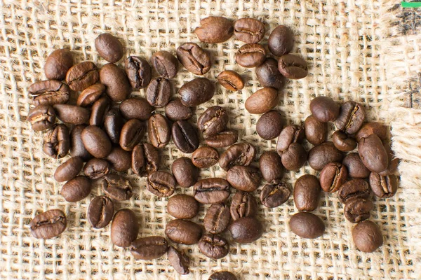 Roasted coffee beans on rustic bag — Stock Photo, Image