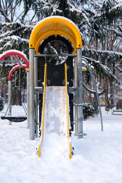 Empty slide in snow covered park — Stock Photo, Image