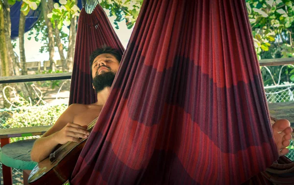Man playing guitar in a hammock — Stock Photo, Image