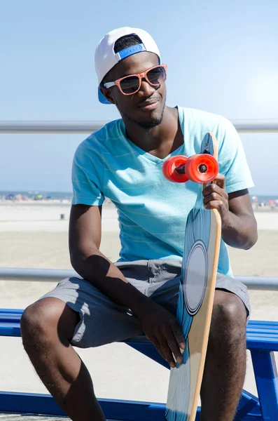 Man holding skateboard at a boardwalk — Stock Photo, Image