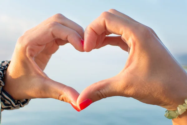 Mujer manos haciendo forma de corazón en la playa — Foto de Stock