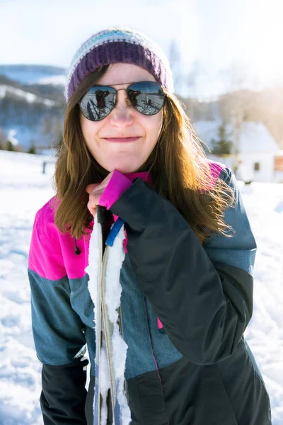 Chica haciendo una cara divertida apoyándose en esquís — Foto de Stock