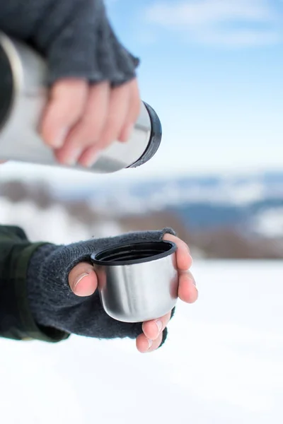 Человек, использующий термос на снежной горе — стоковое фото