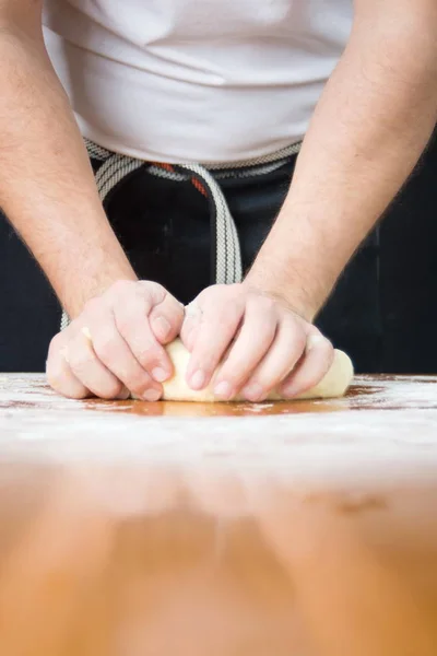 Человек смешивает тесто на крытом мукой столе — стоковое фото