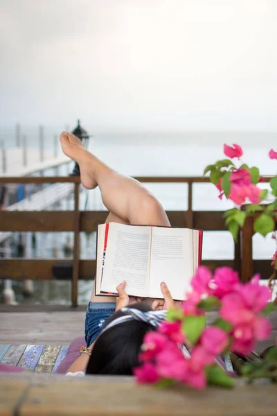 Menina leitura livro na varanda com vista para o mar — Fotografia de Stock