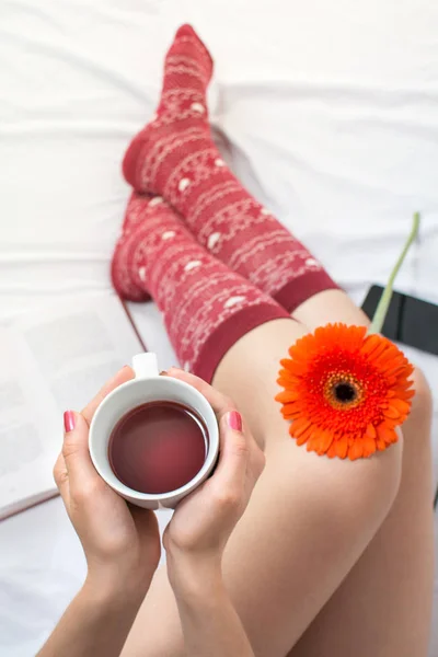 Wanita memegang secangkir teh di tempat tidur — Stok Foto
