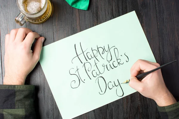 Mãos masculinas escrevendo um cartão feliz dia St Patrick — Fotografia de Stock