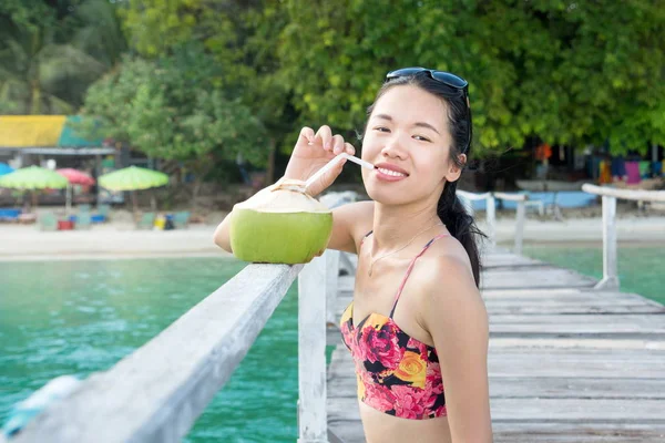 Девушка пьет кокосовую воду на причале — стоковое фото