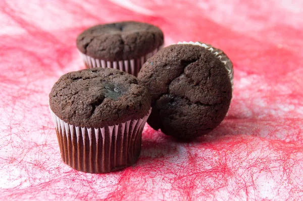 Schokoladenmuffins auf rotem Hintergrund — Stockfoto