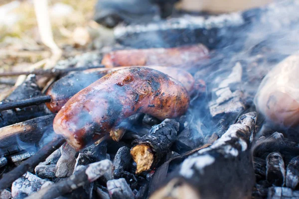 Salsicce arrostimento su braci in fiamme all'aperto — Foto Stock