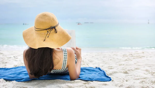 Menina lendo um livro em uma praia de areia — Fotografia de Stock