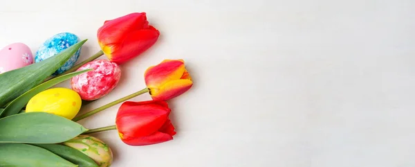 Červené tulipány a malovaná velikonoční vajíčka — Stock fotografie
