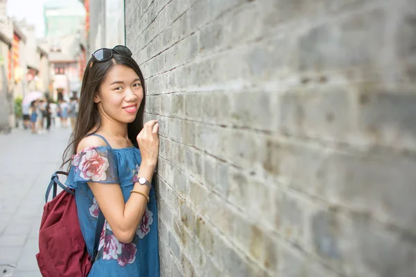 Menina asiática de pé por uma parede de pedra — Fotografia de Stock