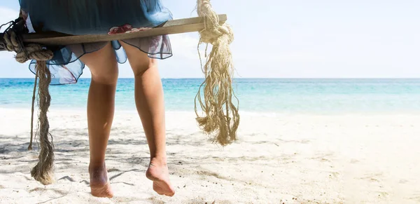 Žena sedí na dřevěnou houpačku na pláži — Stock fotografie