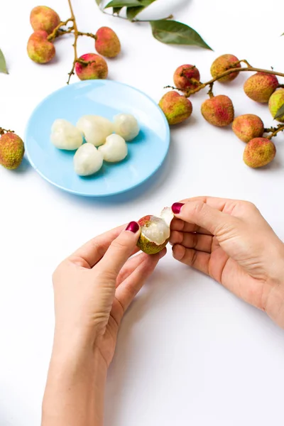Female hands peeling lychee fruit