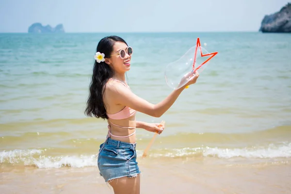 Chica haciendo burbujas de jabón en una playa — Foto de Stock