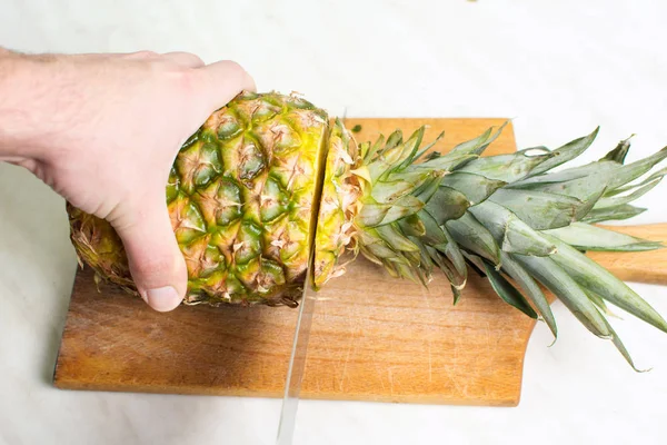 Man snijden ananas op een houten bord — Stockfoto