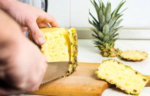 Mannelijke handen peeling huid van verse ananas — Stockfoto