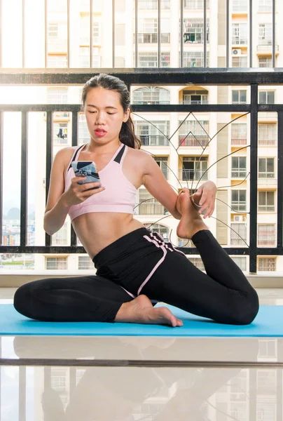 Bir yoga mat üzerinde evde telefon kullanan kız — Stok fotoğraf