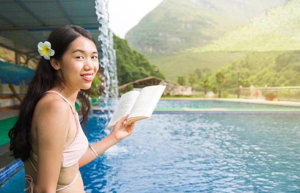 Menina de biquíni lendo um livro na piscina — Fotografia de Stock