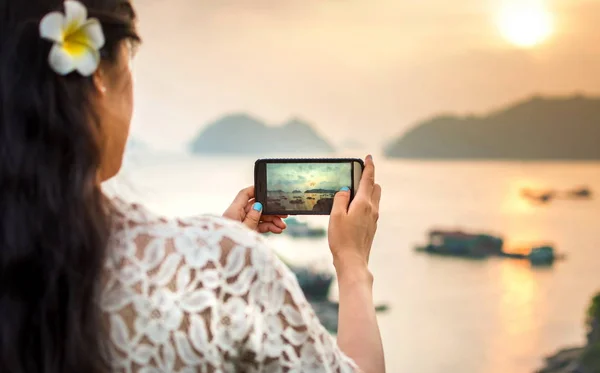 Chica tomando foto al atardecer junto al mar con teléfono inteligente — Foto de Stock