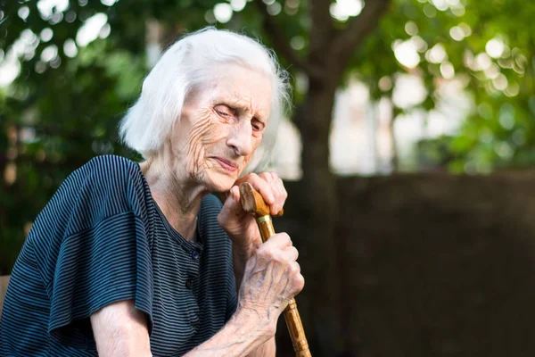 Старшая женщина плачет с тростью — стоковое фото