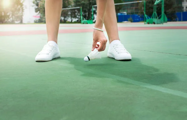 Dívka shromažďování Badmintonové míče na hřišti — Stock fotografie