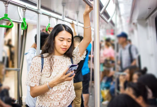Asiatisk tjej med telefon på tunnelbanan — Stockfoto