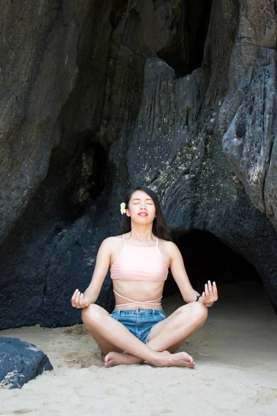 Fille pratiquant le yoga à l'ombre d'une grotte de plage — Photo