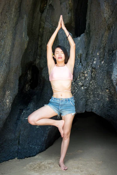 Fille pratiquant le yoga à l'ombre d'une grotte de plage — Photo